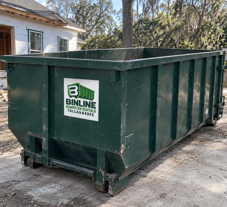 Green Binline Dumpster Rentals Tallahassee roll-off dumpster parked on the driveway of a house under renovation