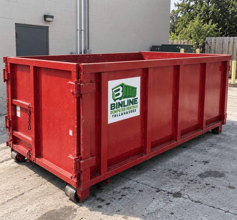 Side view of a red roll-off dumpster showing the Binline Dumpster Rentals Tallahassee logo, the side ribs and the rear door hinges